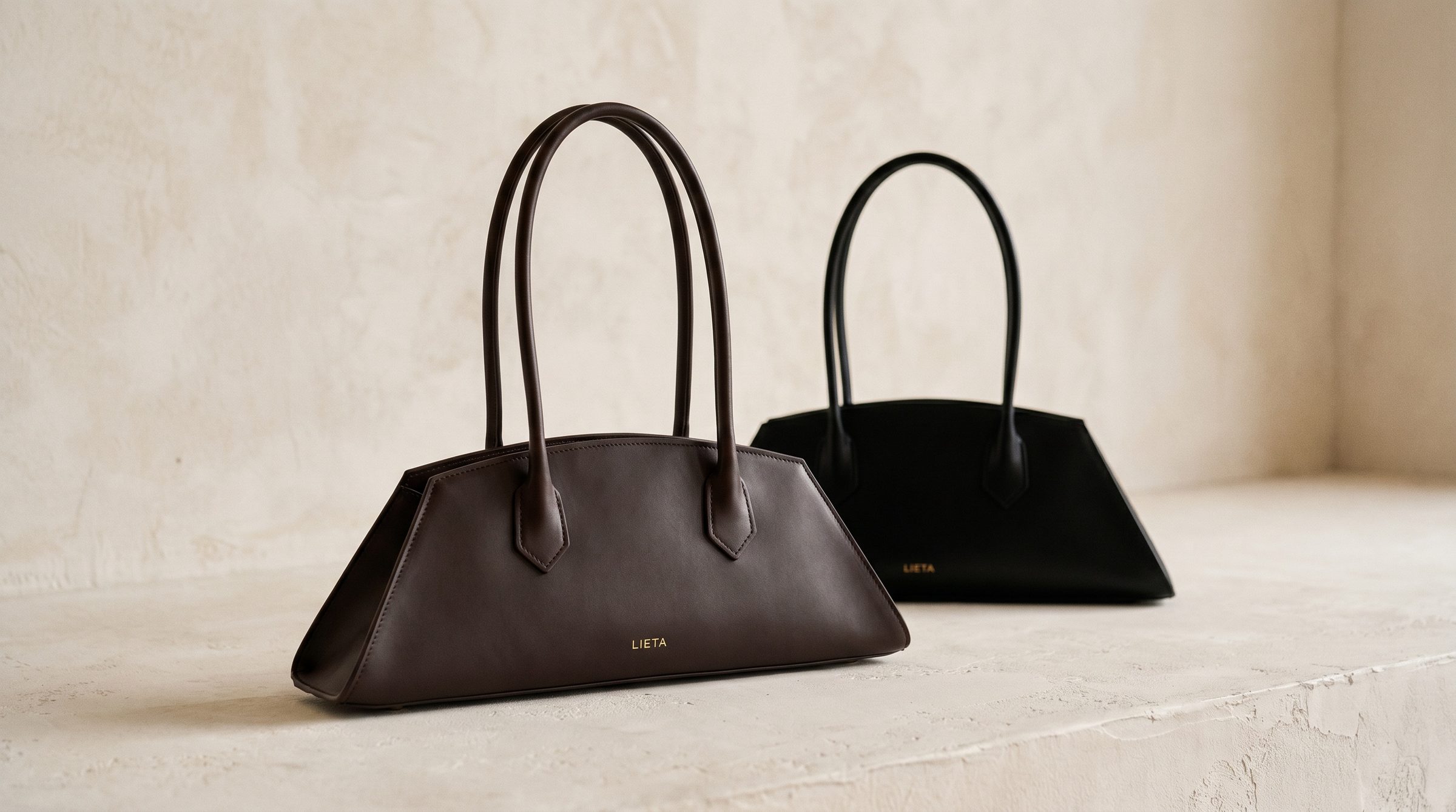The Lungo in chocolate Italian calf leather on a travertine ledge in a Tuscan courtyard at golden hour — accessible-luxury bag in the Birkin register.