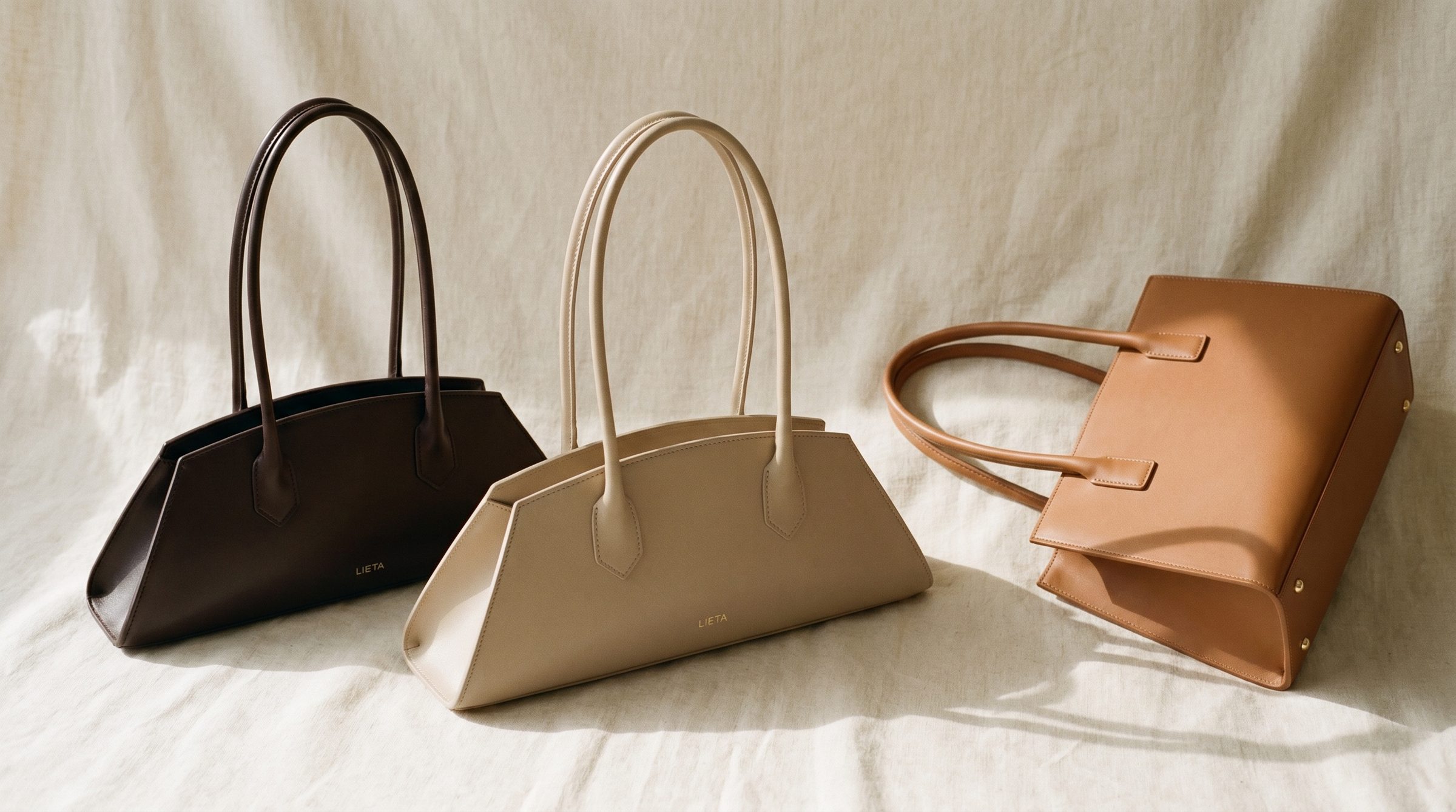 The Lungo in chocolate Italian Buttero leather on a near-white studio background — a silhouette and material category comparable to Cuyana's signature totes.