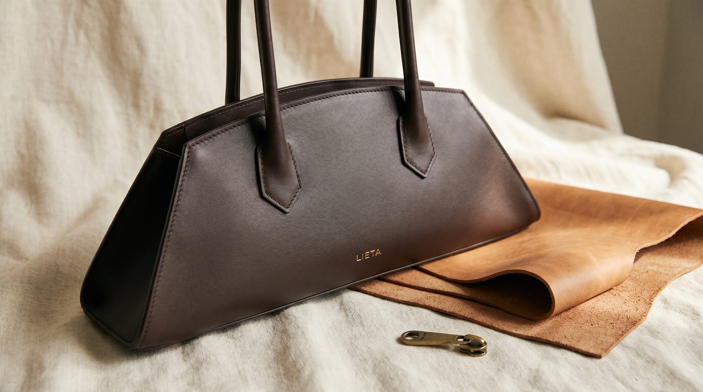 The Lungo in cream Italian Buttero leather on a near-white studio background — a minimalist, unbranded silhouette in the same accessible-luxury register Mansur Gavriel established.