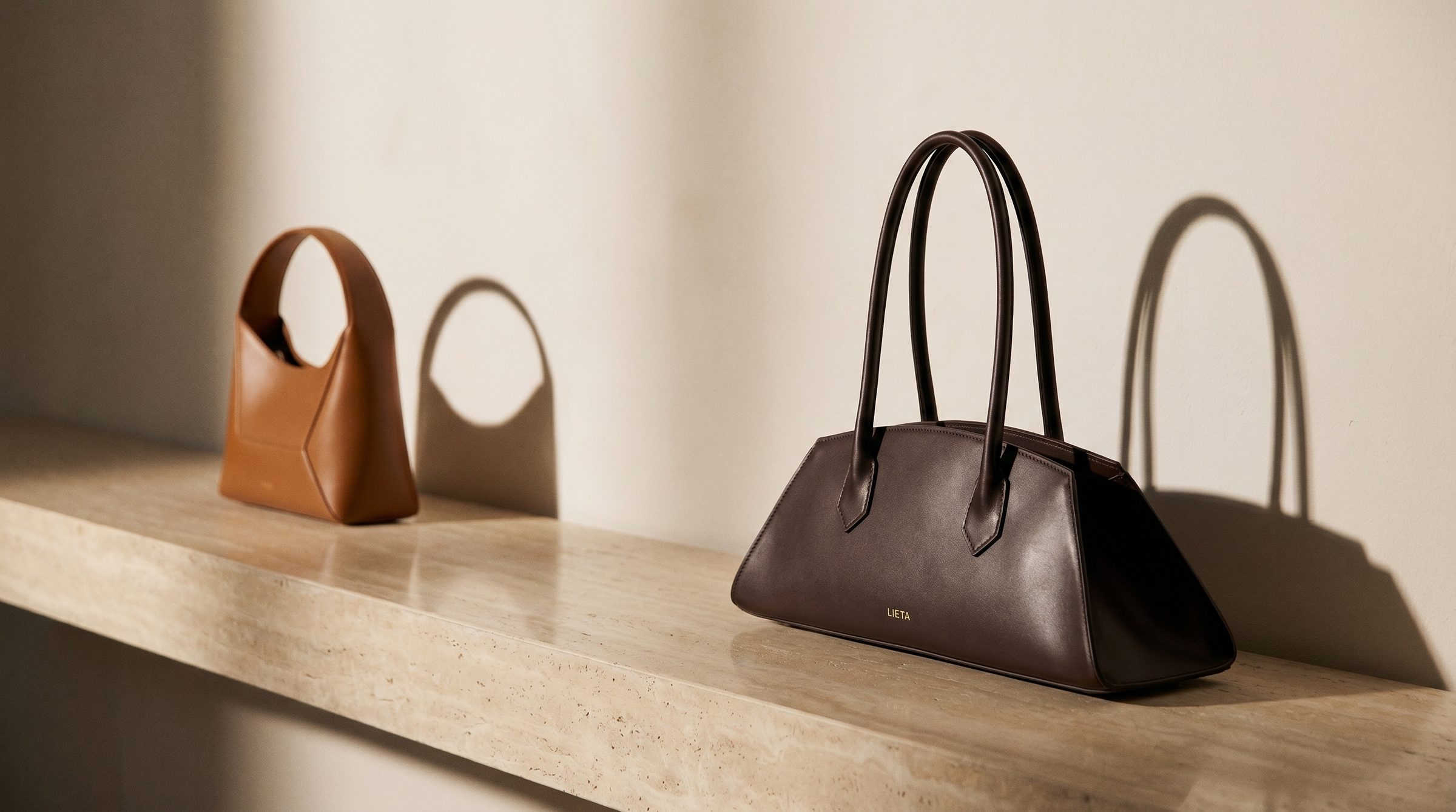 The Lungo in chocolate Italian Buttero leather against a clean editorial backdrop — east-west top-handle silhouette in the broader 'considered European leather' tier Wandler also occupies.